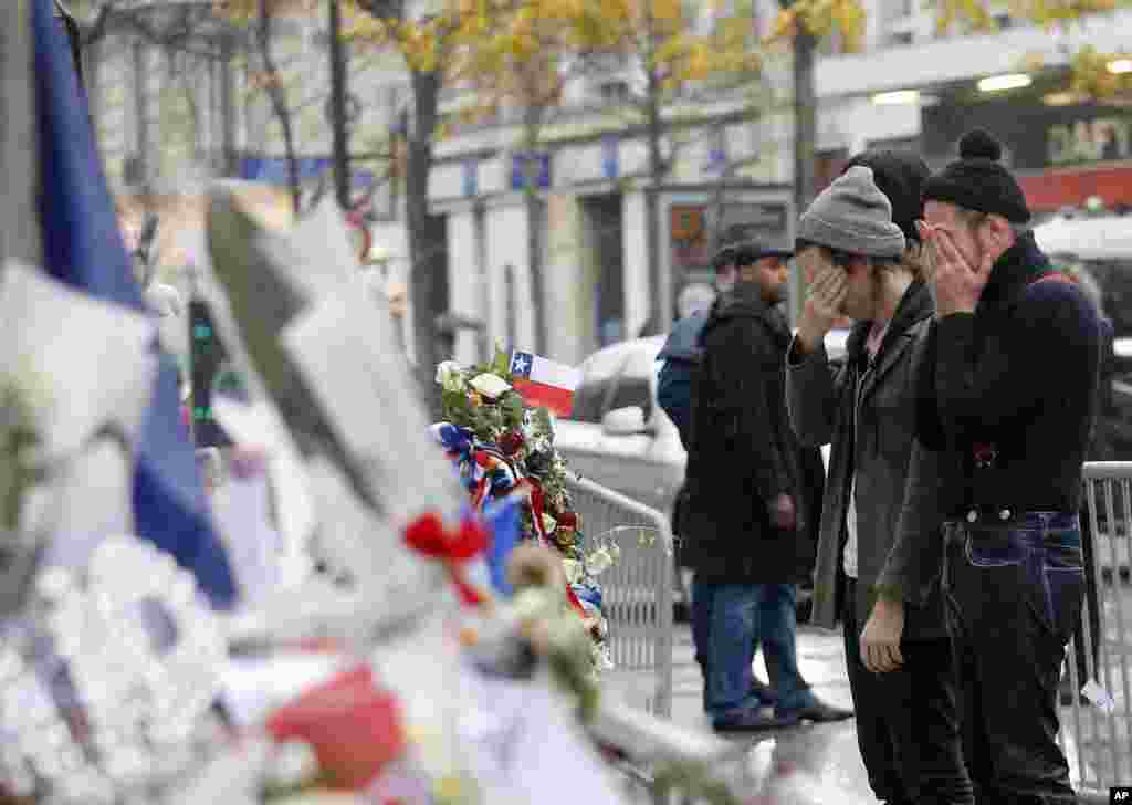Members of the band Eagles of Death Metal, Jesse Hughes, right, and Julian Dorio pay their respects to victims who died in the Nov. 13 terrorist attack, at the Bataclan concert hall in Paris, France. Members of the California rock band are back at the ravaged Paris theater where they survived a massacre by Islamic extremists.