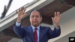 FILE - Former dictator Jean-Claude 'Baby Doc' Duvalier waves to supporters from the balcony of a rented guest house where he is staying in Port-au-Prince.