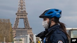 A policewoman wears a mask to protect herself against the spread of the new coronavirus, left, patrols at the garden of the Eiffel Tower in Paris, Monday, April 6, 2020. For most people, the new coronavirus causes only mild or moderate symptoms,…