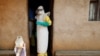 FILE - Health care workers enter a house where a baby suspected of dying of Ebola is, during the baby's funeral in Beni, North Kivu province, Democratic Republic of the Congo, Dec. 18, 2018. 