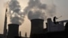 FILE - A laborer works near cooling towers of a power plant on the outskirts of Xiangfan, Hubei province, Nov. 24, 2010.