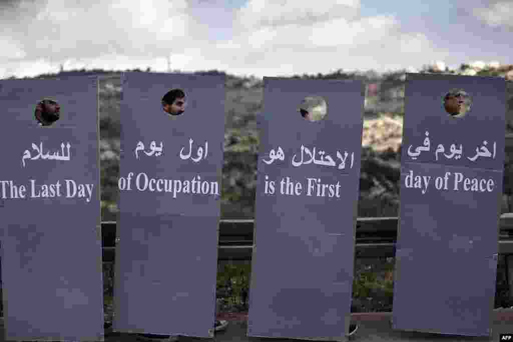 Israeli and Palestinian peace activists walk behind cardboard cut-outs depicting the controversial Israeli separation barrier during a peace march at an Israeli road, near a checkpoint between the West Bank city of Beit Jala and Jerusalem.