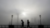 People jog past the Pudong Financial District shrouded with fog and pollution at the Shanghai Bund in Shanghai, China, Thursday, April 14, 2016. 
