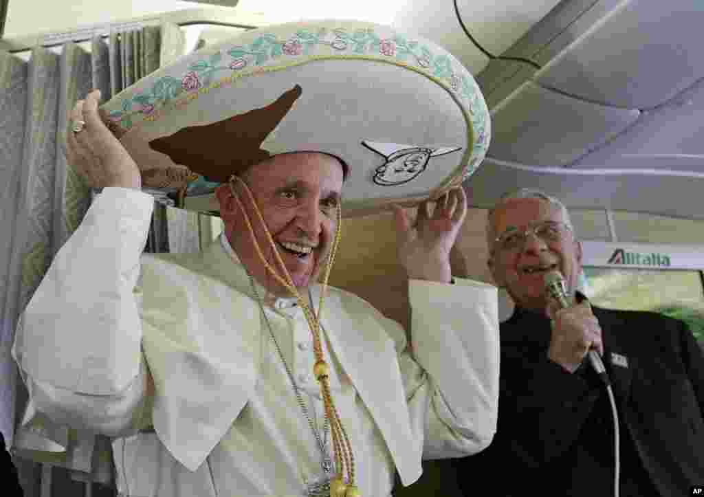 Pope Francis wears a traditional Mexican sombrero hat he received as a gift by a Mexican journalist aboard the plane during the flight from Rome to Havana, Cuba, on his way to a week-long trip to Mexico.