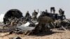 Military investigators from Russia stand near the debris of a Russian airliner at the site of its crash at the Hassana area in Arish city, north Egypt, Nov. 1, 2015.