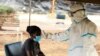 FILE - A woman has her temperature checked by a health care worker during a nationwide lockdown to help curb the spread of the coronavirus, at a screening center in Harare, Zimbabwe, April 30, 2020.