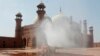 FILE - Volunteers disinfects the historical Badshahi Mosque ahead of the Muslim fasting month of Ramadan, in Lahore, Pakistan, April 22, 2020. 
