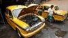 A mechanic repairs a yellow ambassador taxi at a workshop in Kolkata, May 25, 2014.