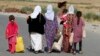 FILE - Women and children from the minority Yazidi sect, fleeing the violence in the Iraqi town of Sinjar, walk to a refugee camp after they re-entered Iraq from Syria at the Iraqi-Syrian border crossing in Fishkhabour, Dohuk province, Aug. 14, 2014.
