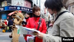 A Japanese tourist (R) speaks to a volunteer interpreter in Central Seoul April 8, 2013.