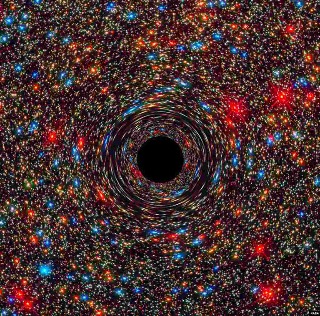 This computer-simulated image shows a supermassive black hole at the core of a galaxy. The black region in the center represents the black hole’s event horizon, where no light can escape the massive object’s gravitational grip. Light from background stars skims by the black hole. (Credits: ESA, and D. Coe, J. Anderson, and R. van der Marel (STScI)