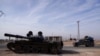 Sebuah mobil bergerak melewati tank yang terabaikan di Aleppo, Suriah, pada 11 Desember 2024. (Foto: Reuters/Karam al-Masri)