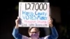 Demonstrator Gina Dusterhoft holds up a sign as she walks to join others standing across the street from the federal courthouse in Houston, Texas, Nov. 2, 2020, before a hearing involving drive-thru ballots cast in Harris County.