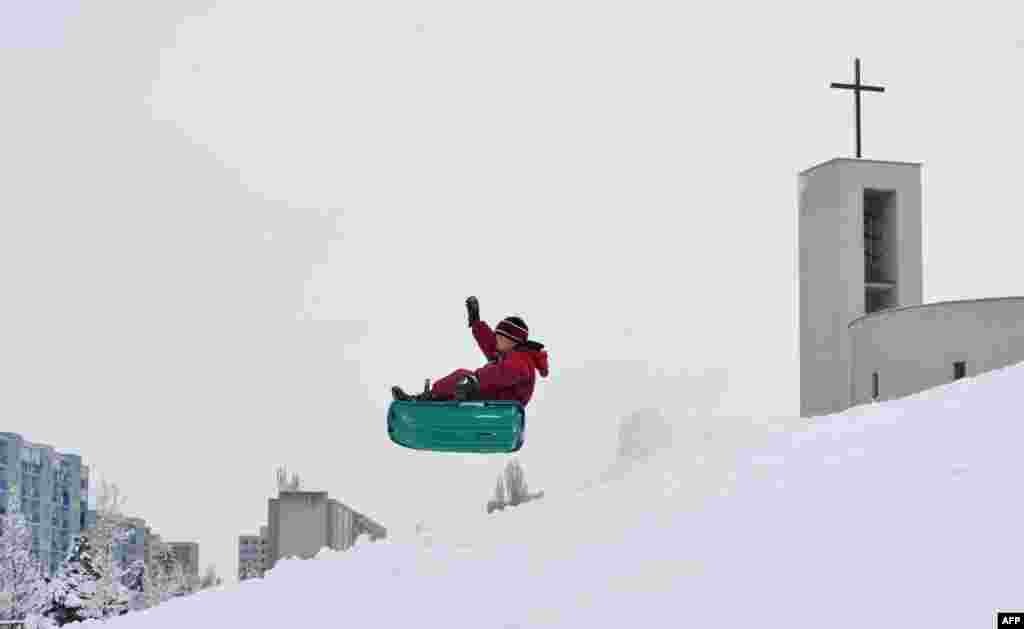 A boy enjoys sledding after a heavy snowfall in Prague, Czech Republic.