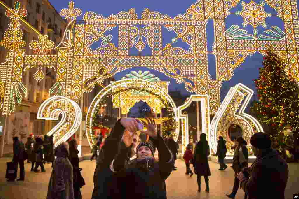 Young people take a selfie in front of decorations for New Year's celebration on Tverskaya street in Moscow, Russia.
