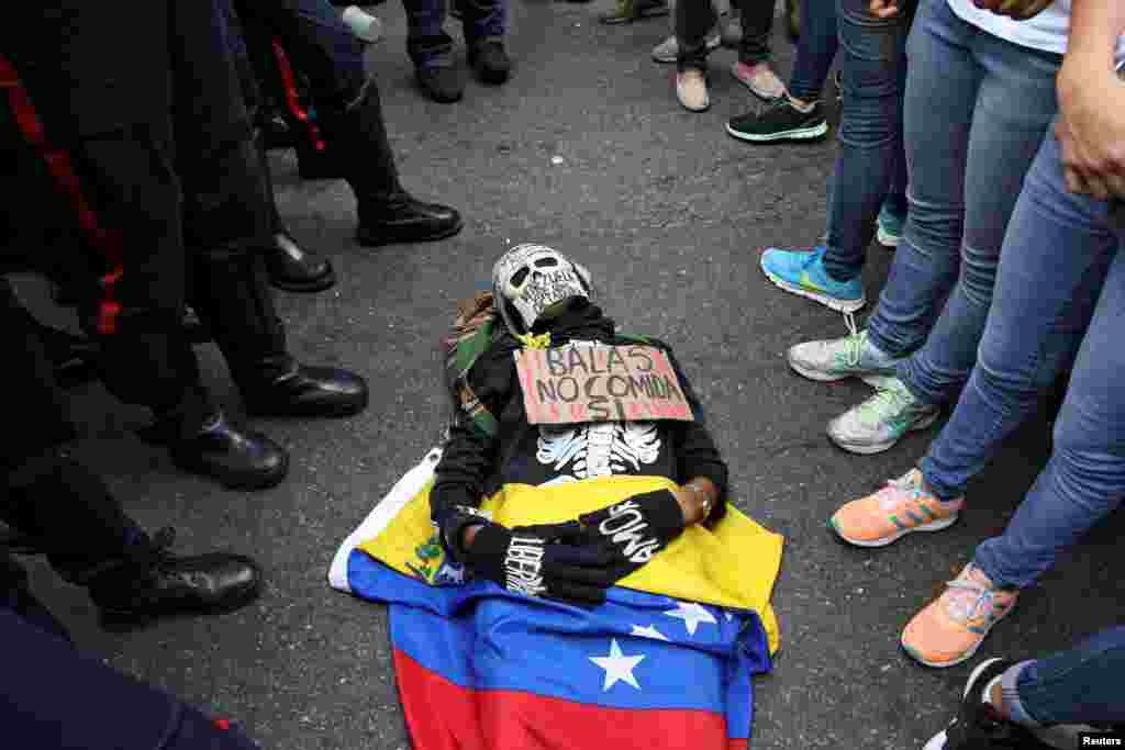 Seorang pendukung oposisi yang mengenakan kostum yang bertulisan &quot;Peluru Tidak, Makanan: Ya&quot; berbaring di lantai saat aksi protes anti-Presiden Nicolas Maduro di Caracas, Venezuela.