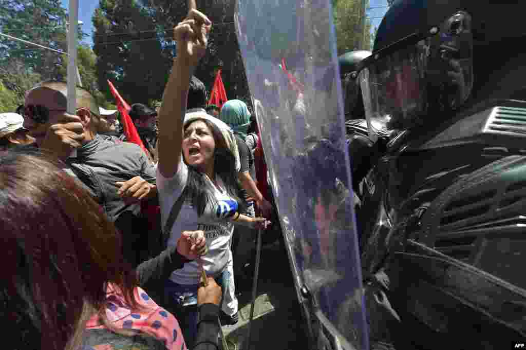 People face policemen during a demonstration against a constitutional amendment which would allow indefinite re-election in front of a line of riot policemen in Quito, Ecuador.