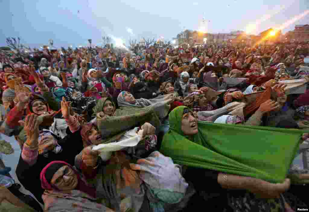 Kashmiri Muslim women raise their arms as they pray upon seeing a relic of Prophet Mohammad being displayed during the festival of Eid-e-Milad-ul-Nabi at Hazratbal shrine on a cold winter morning in Srinagar, India.