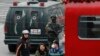 People walk past an armed Chinese paramilitary policeman standing guard in the capital city's popular shopping and nightlife area of Sanlitun in Beijing, Dec. 27, 2015.