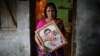 Fatema holds a picture of her son Nurul Karim as she poses for a photograph in front of her house in Savar, April 21, 2014. Fatema lost her son and her daugther Arifa, who were working at the Rana Plaza when it collapsed on April 24, 2013.