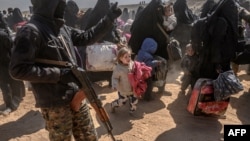 FILE - Women and children evacuated from the Islamic State group's holdout of Baghuz arrive at a screening area held by the U.S.-backed Syrian Democratic Forces, in the eastern Syrian province of Deir el-Zour, March 6, 2019.