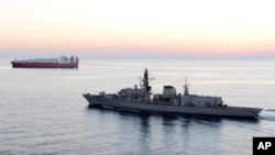 FILE - Britain'sHMS Montrose escorts a ship off the coast of Cyprus in February 2014. Britain has started sending a warship to accompany all British-flagged vessels through the Strait of Hormuz; the Montrose was the first to do so, on July 24, 2019.