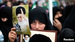 FILE - A woman holds pictures of Iran's Supreme Leader Ayatollah Ali Khamenei (top) and late Leader Ayatollah Ruhollah Khomeini during a rally to mark the 32nd anniversary of the Islamic Revolution in Qom, February 11, 2011. REUTERS/Morteza Nikoubazl