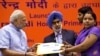 Indian Prime Minister Narendra Modi hands over a banking kit to an unidentified woman at the launch of a campaign aimed at opening millions of accounts for poor Indians in New Delhi, India, Aug. 28, 2014.