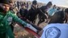 Les manifestantas palestiniens transportent un blessé près de la frontière avec l'Israel. 