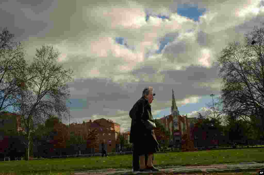 An elderly couple walk past along public park of the city during a mild winter day in Pamplona, northern Spain.