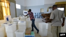 Les gens comptent les boîtes et le matériel électoral reçus dans un centre de distribution de la commune de Port-Bouet à Abidjan, le 24 octobre 2015.