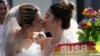 FILE - Women in wedding gowns kiss while holding a poster in support of marriage equality, during a Pride Parade in Bangkok, Thailand, June 4, 2023. A marriage equality bill sailed through both Thailand's House of Representatives and the Senate in April and June respectively.