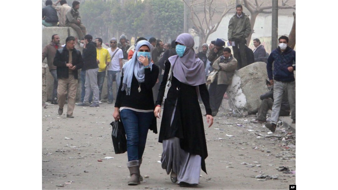 Misr inqilobida ayollar faol ishtirok etdi. Suratda Qohira ko'chalarida namoyishchilarga qarata otilgan ko'zdan yosh chiqaruvchi gazdan o'zini himoyalash maqsadida yuziga niqob taqib olgan ikki misrlik ayol aks etgan. 6-fevral, 2012-yil.