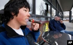Jameson Florence, left, and Mark Jablonski as they smoke La Traviata cigars outside the Rain City Cigar shop in Seattle.