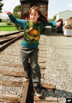 Actress Mara Wilson balances herself as she walks the rails as she relaxes during a lunck break in the filming of "Thomas and the Magic Railroad" in Strasburg, Pennsylvania, Sept. 13, 1999.
