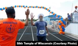 A man completes the Sikh Temple of Wisconsin's 6k "Chardhi Kala" Run with a high five.