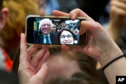 FILE - A supporter of Democratic presidential candidate Sen. Bernie Sanders, I-Vt., takes a selfie with the candidate during a campaign rally in Minneapolis, Minnesota, Feb. 29, 2016. Many states are weighing allowing selfies with voters' ballots.