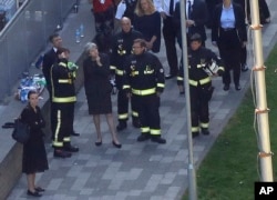 FILE - Britain's Prime Minister Theresa May, center, speaks to firefighters after arriving at Grenfield Tower in London, June 15, 2017, following a deadly fire in the apartment block.