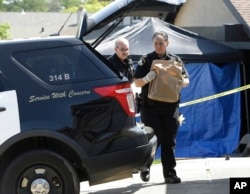Sacramento sheriff's deputies carry evidence taken from the home of suspect Joseph DeAngelo to a sheriff's vehicle, April 26, 2018, in Citrus Heights, Calif. DeAngelo, 72, was taken into custody, Tuesday, on suspicion of committing at least 12 slayings and a number of rapes.