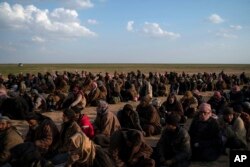 Men wait to be screened by U.S.-backed Syrian Democratic Forces fighters after being evacuated out of the last territory held by Islamic State militants, near Baghuz, eastern Syria, Feb. 22, 2019.