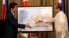 Japanese Prime Minister Shinzo Abe, left, and Philippine President Benigno Aquino III shake hands after Abe presented him with a topographical map of the country's third largest island of Mindanao at the conclusion of their joint press statement at Malaca