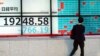 A man looks at an electronic stock board showing Japan's Nikkei 225 index at a securities firm in Tokyo, Jan. 4, 2019. Japanese markets have tumbled as they reopened after the New Year holidays, while other Asian indexes are mixed after a technology-led sell-off on Wall Street.