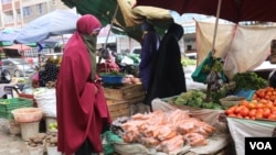 A woman buys vegetables from a local vendor in the Eastleigh neighborhood of Nairobi. The neighborhood is under lockdown after a spike in COVID-19 cases. (Mohammed Yusuf/VOA)