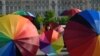 People hold rainbow umbrellas to celebrate International Day Against Homophobia, Biphobia and Transphobia in the front of the Romanian Parliament building in Bucharest, May 17, 2016. 