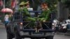 FILE - Policemen sit in the back of a truck in Hanoi, Vietnam, March 1, 2019.