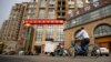 FILE - A delivery cart and cyclist ride past a building housing the Fengrui law firm in Beijing. Observers say China has shown little sign of easing its clampdown on rights defenders one year after the government arrested and interrogated nearly 320 human rights lawyers and activists.