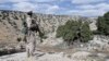 FILE - A Lebanon Hezbollah fighter carries his weapon as he stands in Khashaat, in the Qalamoun region, May 15, 2015. 