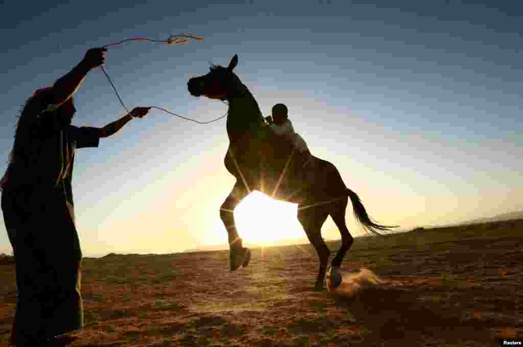 A Saudi man trains his son to ride a horse in a desert near Tabuk, Saudi Arabia.