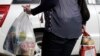 FILE - A shopper leaves a supermarket with goods in plastic bags in Christchurch, New Zealand, Aug. 10, 2018. 