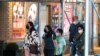 Masked people walk past posters advertising theater shows as the U.S. registers a surge in infections with the highly transmissible delta variant of the coronavirus, in New York City, July 30, 2021.